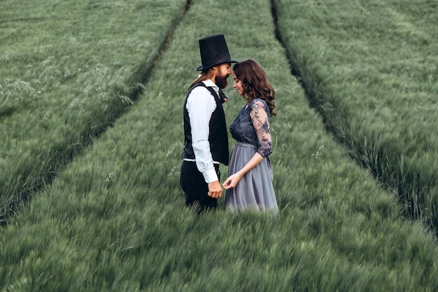 Élégante mariée et le marié marchant et posant sur champ vert