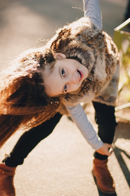 Élégante petite fille de 4 à 5 ans portant des bottes, un manteau de fourrure, se déplaçant et jouant. Automne saison d'automne