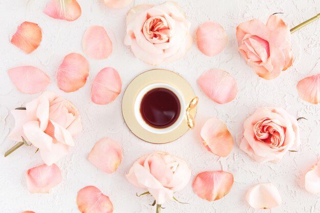 Élégante tasse de café avec des fleurs roses roses et des pétales