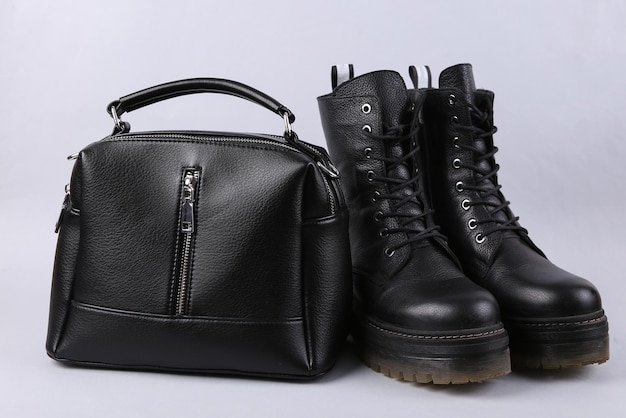 Élégantes bottes en cuir noir et sac à main sur fond gris