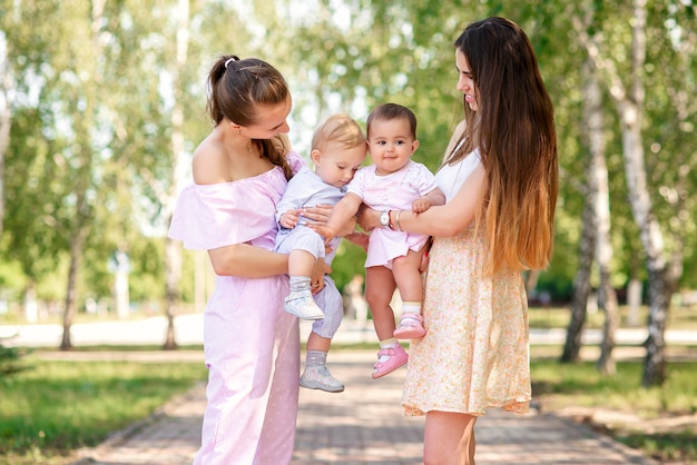 Élégantes jeunes mères marchant dans le parc urbain avec leurs filles. De belles petites filles jouent les unes avec les autres.