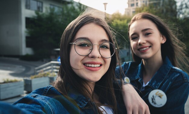 Élégants meilleurs amis heureux faisant selfie