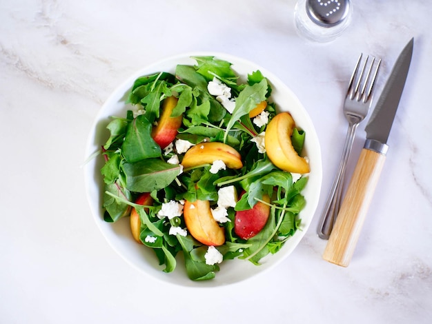 Une légère salade d'été de rucolla pêches et fromage sur fond clair