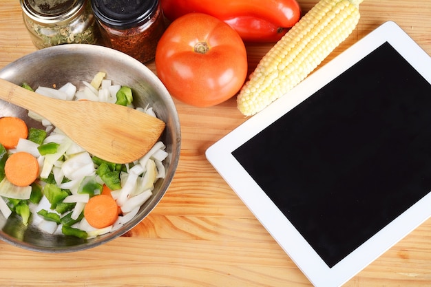 Légumes et assaisonnements avec une tablette numérique.