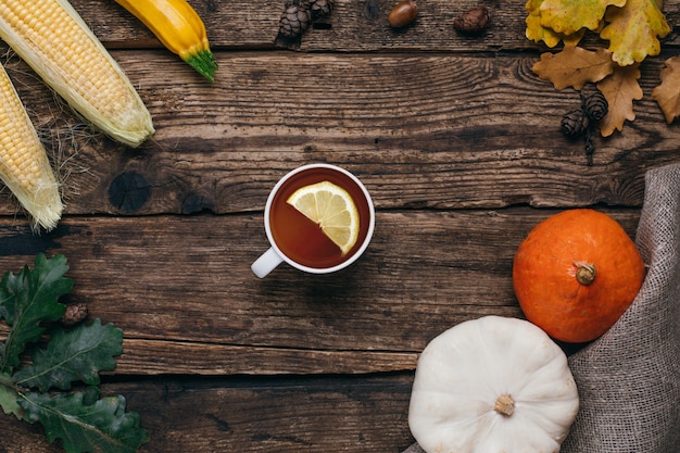 Légumes D'automne: Thé, Citrouilles Et Maïs à Feuilles Jaunes Sur Bois