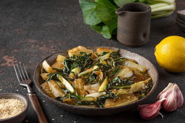 Légumes bok choy sautés avec sauce soja et graines de sésame sur fond sombre. Cuisine chinoise. Nourriture végétalienne saine. fermer