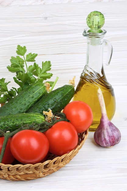 Légumes et une bouteille d'huile d'olive sur un fond en bois clair