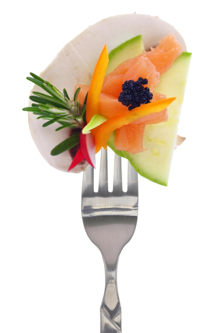 Légumes colorés saumon et caviar sur fourche isolés sur blanc