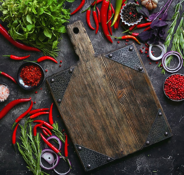 Légumes crus frais et planche à découper vide sur fond sombre