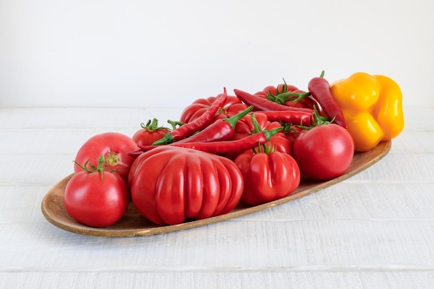 Légumes crus mûrs dans un plat sur une table en bois rustique blanche