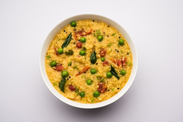 Légumes Dalia ou Daliya Khichadi ou Broken Wheat Khichdi avec tomate, pois verts et piment, servi dans un bol ou une assiette