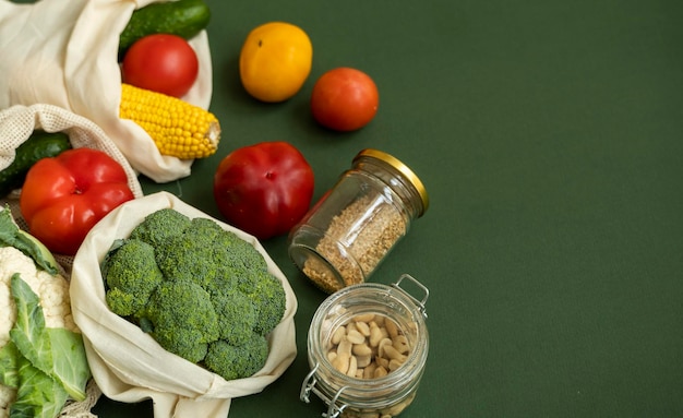 Photo légumes dans un sac écologique et noix dans un bocal en verre sur une surface verte zéro déchet sans plastique