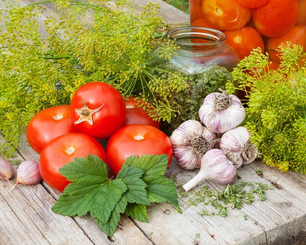 Légumes et épices sur planche de bois Tomates en conserve maison dans un bocal en verre