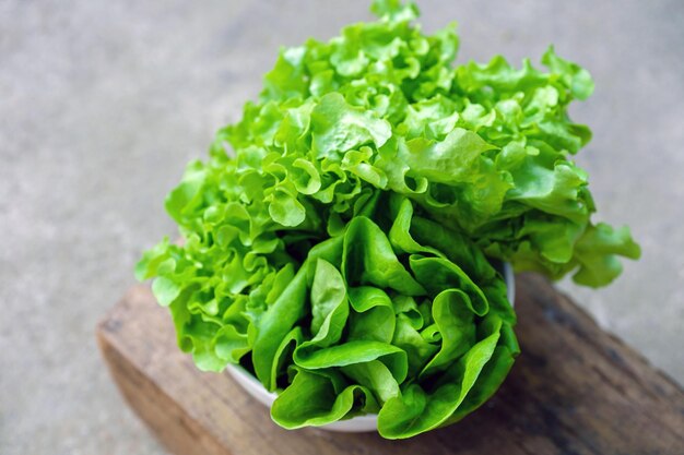 Photo les légumes-feuilles ou la laitue dans un bol blanc sur fond de bois sont un aliment qui ajoute des fibres au corps