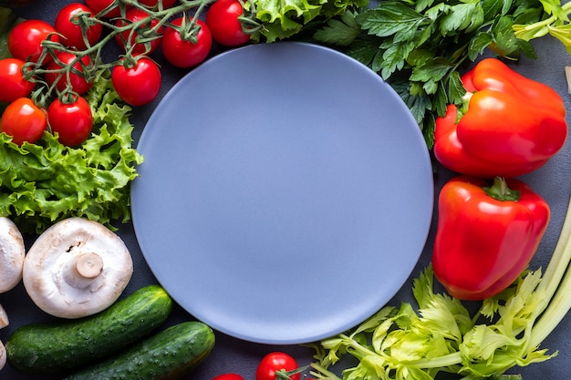 Légumes frais autour d'une assiette vide.