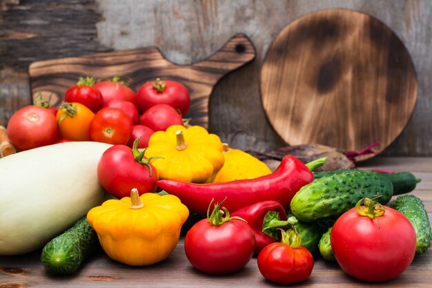 Légumes frais - courges, concombres, tomates, courgettes, poivrons sur une table en bois