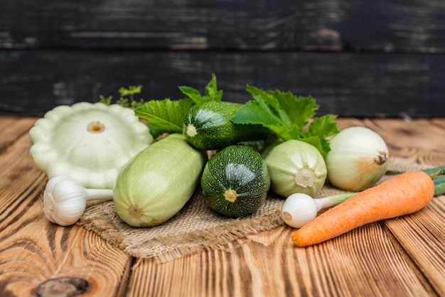 Légumes frais, courgettes, concombres, carottes et verts sur un fond en bois