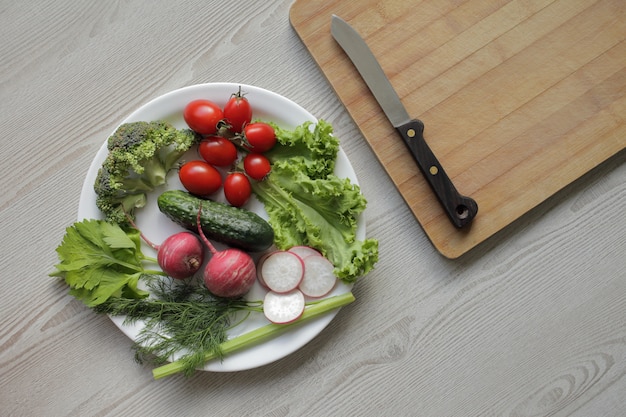 Légumes frais dans une assiette blanche sur une table en bois clair