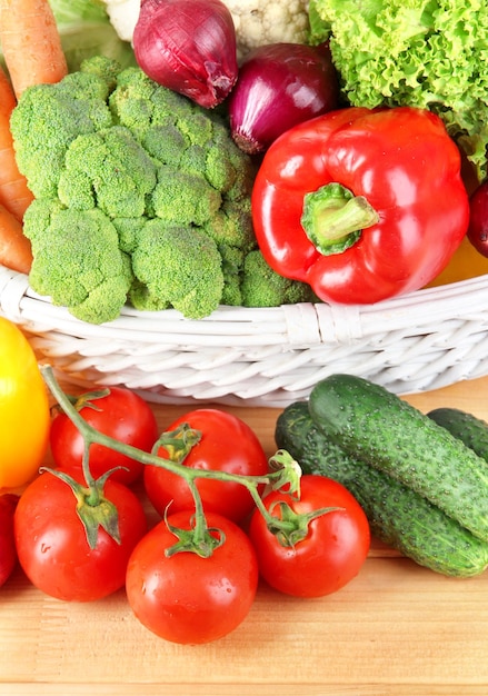 Légumes frais dans un panier en osier blanc sur fond de bois