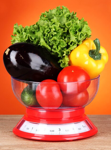 Légumes frais en écailles sur table sur orange