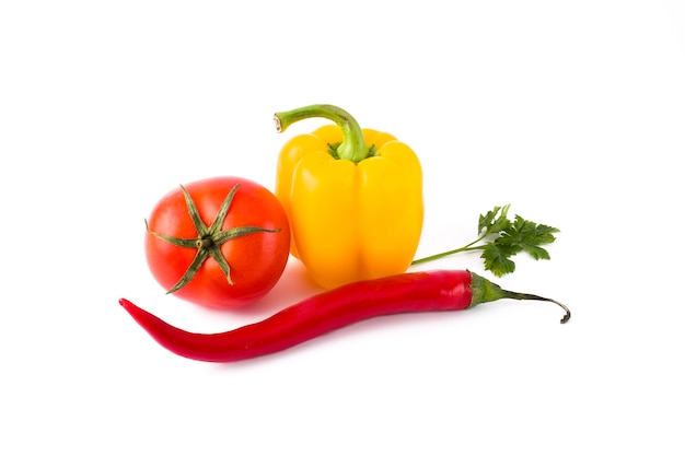 Légumes frais sur fond blanc Poivron jaune, tomate rouge et poivron amer sur fond blanc.
