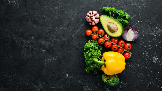 Légumes frais sur fond noir Avocats tomates ail persil paprika Vue de dessus Espace libre pour votre texte