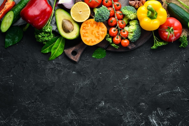 Légumes frais sur fond noir Avocats tomates pommes de terre paprika agrumes Vue de dessus Espace libre pour votre texte