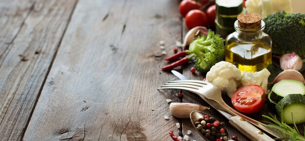 Légumes frais, huile d'olive et épices sur table en bois