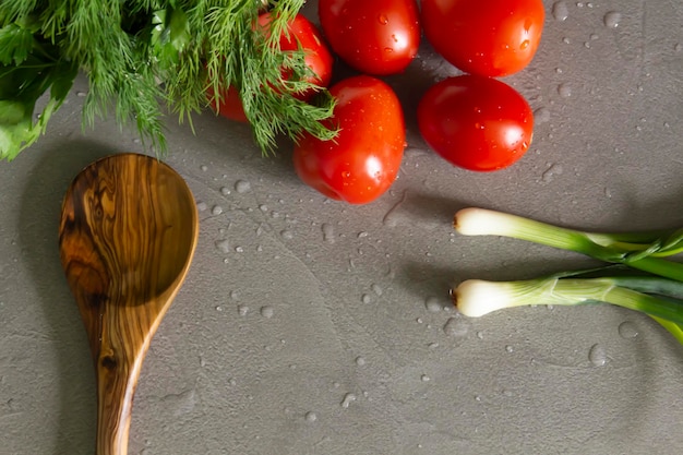 Des légumes frais et parfumés et une cuillère en bambou se trouvent sur la cuisine grise