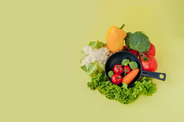 Légumes frais sur une poêle sur fond jaune. Concept végétalien et sain