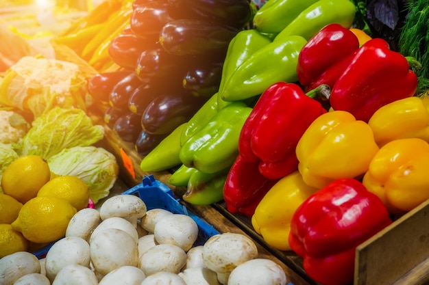 Les légumes frais sont dans un plateau au marché de l'épicerie Belle disposition de légumes colorés et juteux Poivrons rouges et jaunes Aubergines Chou et champignons se trouvent ensemble Fond publicitaire