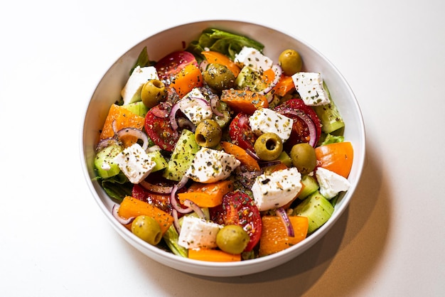 Légumes frais tranchés pour salade dans une assiette sur fond blanc