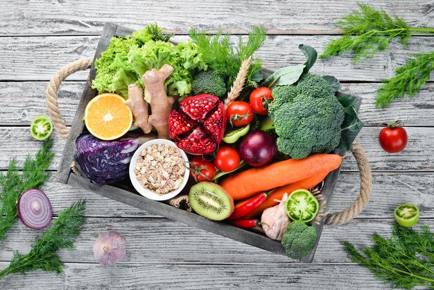 Légumes et fruits frais dans une boîte en bois sur un fond en bois blanc Aliments biologiques Vue de dessus Espace de copie gratuit