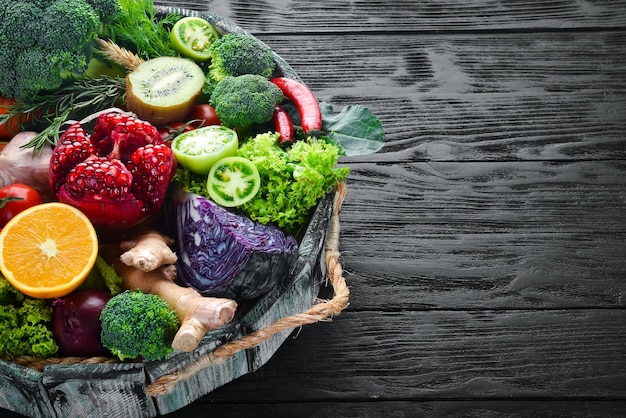 Légumes et fruits frais dans une boîte en bois sur fond noir Aliments biologiques Vue de dessus Espace de copie gratuit