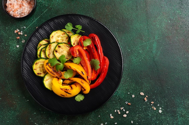 Légumes grillés courgettes, poivrons rouges et jaunes, poivrons et bouquet de coriandre sur lèchefrite. Vue de dessus. Notion de barbecue.