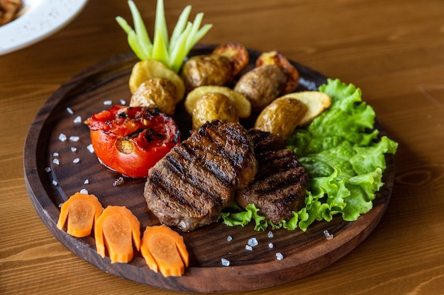 Légumes grillés et un morceau de délicieuse viande grillée sur une table en bois