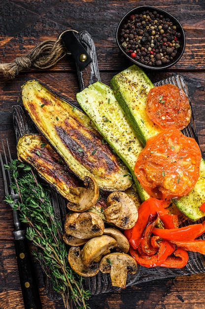 Légumes grillés poivron, courgettes, aubergines et tomates aux herbes sèches sur une planche de bois