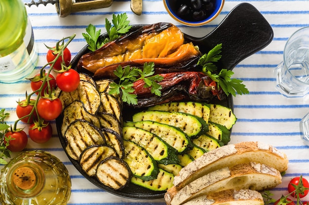 Légumes grillés sur la table avec du vin blanc, du pain frais et des herbes aromatiques. menu d'été