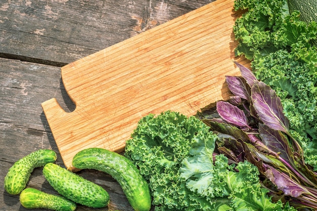 Légumes et herbes biologiques cultivés localement avec planche de cuisine sur une table en bois