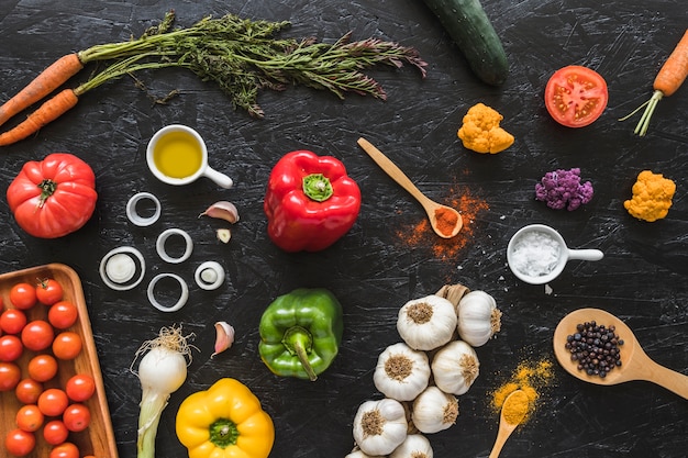 Des légumes; huile et épices sur comptoir noir