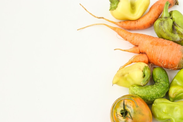 Légumes laids: carottes, concombre, poivrons et tomates sur fond blanc, concept de nourriture laide, photo horizontale, espace copie