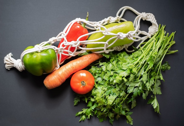 légumes et légumes verts dans un sac à cordes sur fond sombre vue de dessus