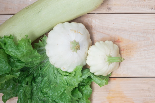 Légumes maison. Courge blanche et laitue sur bois.