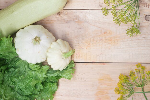 Légumes maison. Courge blanche et laitue sur bois.