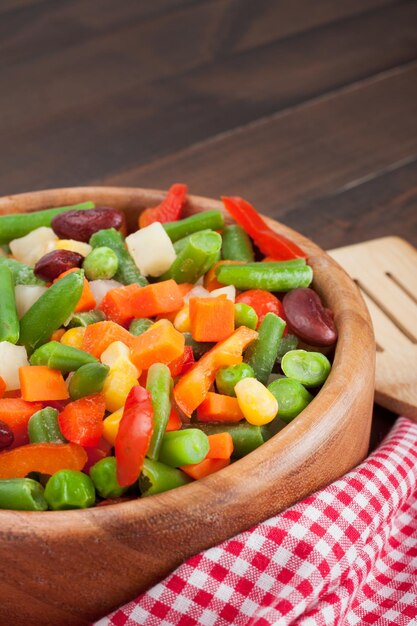 Légumes mélangés dans un bol en bois sur la table de la cuisine