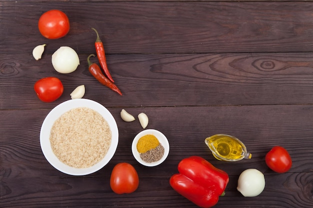 Légumes de riz et épices pour la cuisson du riz jollof sur fond de bois marron Copier les spaes