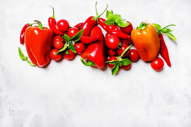 Légumes rouges et basilic vert sur la vue de dessus de fond blanc