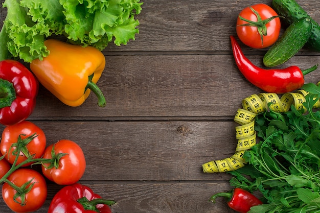 Légumes et ruban à mesurer dans l'alimentation sur la vue de dessus de fond en bois