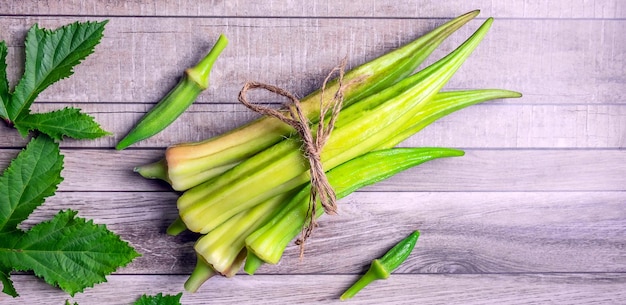 Légumes sains d'okra vert frais et d'okara en feuilles sur fond gris Vue de dessus