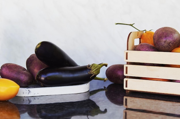 Légumes de saison dans une boîte en bois et sur des podiums tomates fraîches pommes de terre violettes aubergines Préoccupation écologique eco shopping Marché alimentaire équitable